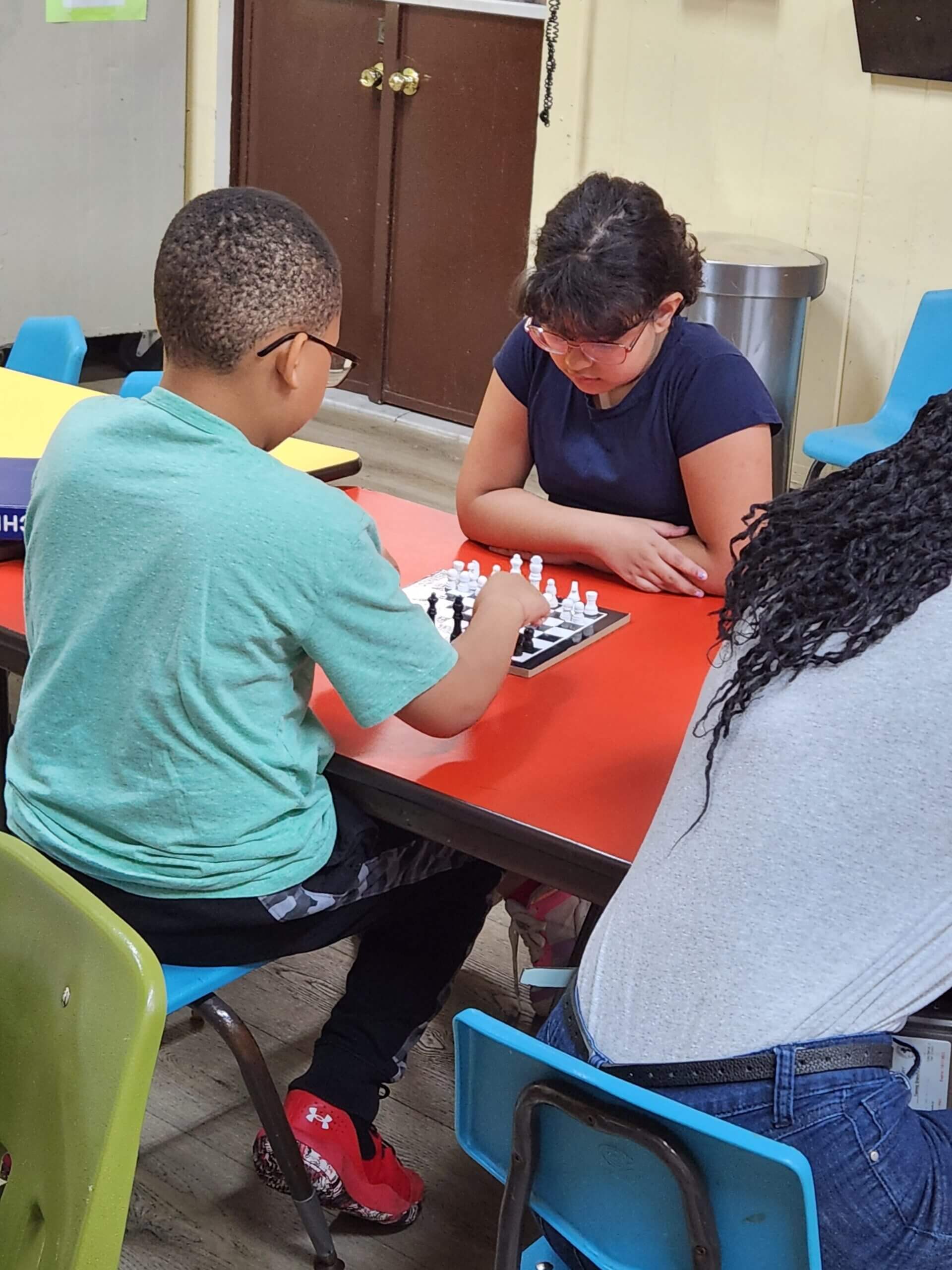 A girl with a boy playing chess on the table